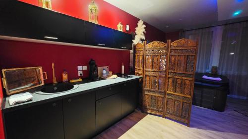 a bathroom with a sink and a red wall at Le Rubis - Votre cocon d'orient in Calais