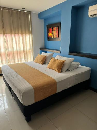 a bedroom with a large bed with blue walls at Hotel Mare Apartasuite in Cali