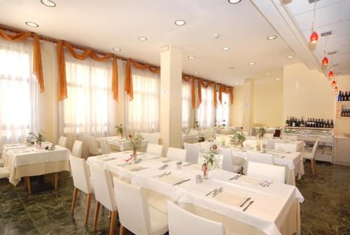 a dining room with white tables and white chairs at Hotel Europa in San Bartolomeo al Mare