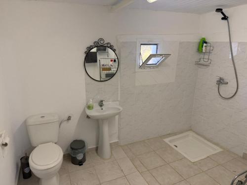 a white bathroom with a toilet and a sink at Villa Maria in Mángana