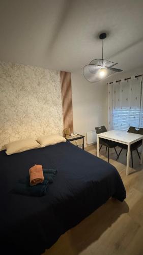 a bedroom with a black bed and a table at Bagnole de l'Orne Studio in Bagnoles de l'Orne