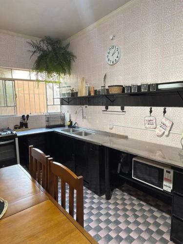 a kitchen with a sink and a clock on the wall at Sobrado completo, confortável e bem localizado in Santo André