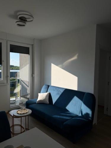 a blue couch in a living room with a window at LUMA Campus Studio in Brčko