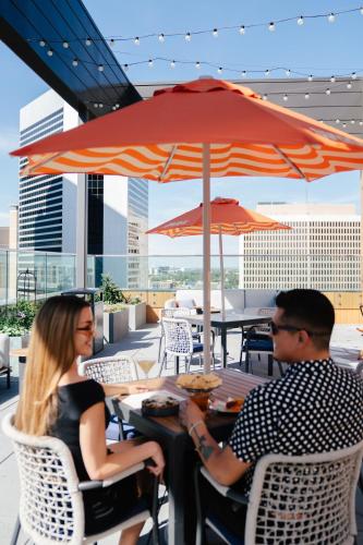 a man and woman sitting at a table under an umbrella at Hyatt Centric Downtown Denver in Denver