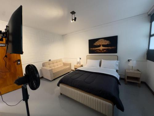 a bedroom with a bed and a tv and a couch at Hostal Casa Iwa in Medellín