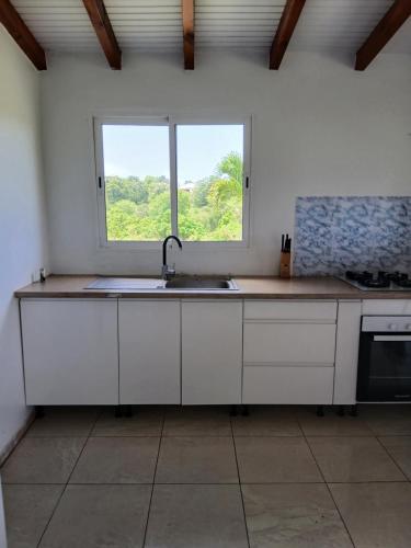 a kitchen with a sink and a window at Jolie maison avec terrasse in Partarieux