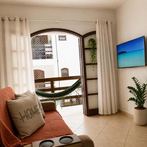 a living room with a couch and a window at TOP 1 QUARTO com ESTACIONAMENTO em Condomínio com VISTA INCRIVEL - PORTARIA 24h, PISCINA, Sauna e Parquinho Infantil - Apartamento com Ar condicionado, Smart TV, Wi-Fi, Cozinha Completa, NETFLIX, Entre o MAR e a LAGOA, CUSTO BENEFICIO in São Pedro da Aldeia