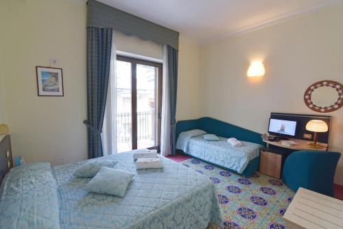 a hotel room with two beds and a television at Hotel Santa Lucia in Minori