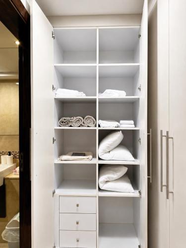 a closet with white shelves and white cabinets at شقة برج رافال Rafal Tower in Riyadh