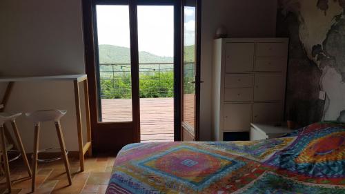 a bedroom with a bed and a door to a deck at Au Royaume des Chats in Soudorgues