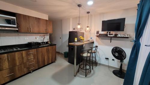 a kitchen with a refrigerator and a counter with stools at Estudio cerca a puerta del norte in Bello