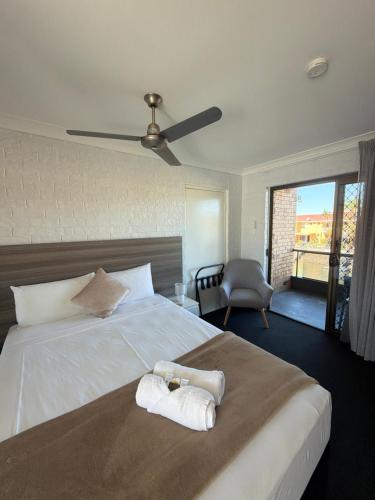 a bedroom with a large bed with two towels on it at Bribie Waterways Motel in Bongaree