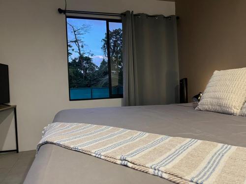 a bedroom with a bed and a window at Altima Arenal Volcano View in Tanque