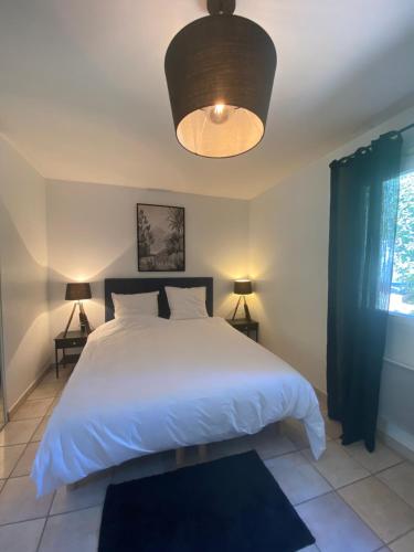 a bedroom with a large white bed and a lamp at Villa Arethuse - Pyla sur Mer in Pyla-sur-Mer