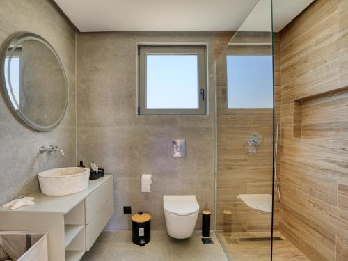 a bathroom with a toilet and a glass shower at Villa Dioni in Kardamaina