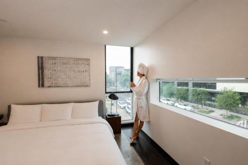 a woman standing in a bedroom looking out the window at Ida Phoenix in Phoenix