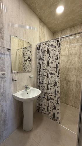 a bathroom with a sink and a shower curtain at Yolyans Hotel in Goris