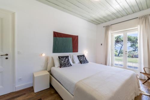 a white bedroom with a large bed and a window at Villa Avola Bol Exclusive Beach Access in Bol