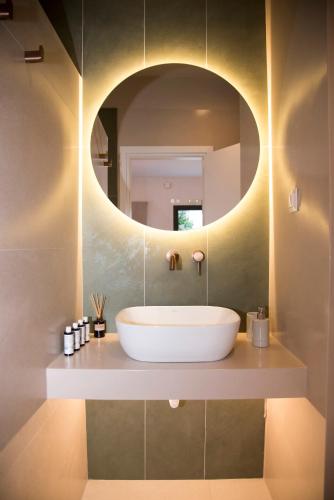 a bathroom with a white tub and a round mirror at Siroa Serene in Rózia