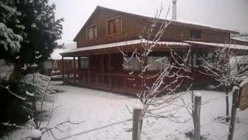 a house with snow on the ground in front of it at Cabañas El Puente Azul in Aluminé