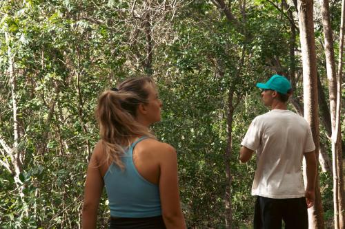 a man and a woman walking through a forest at Mikado Natural Lodge in Playa Avellana
