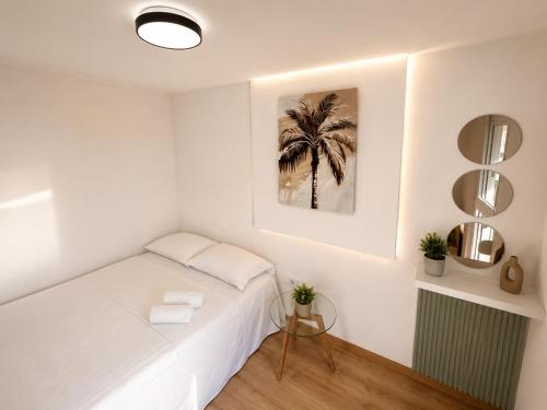 a white bedroom with a bed and a palm tree at Blue Yard in Lepetani
