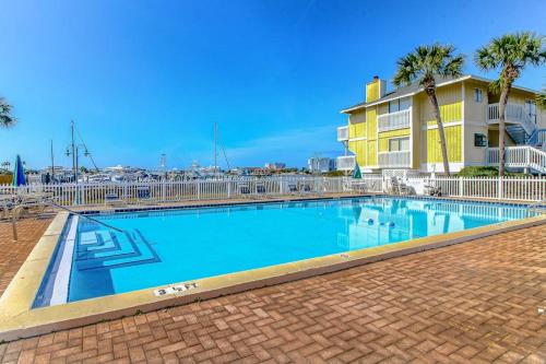 a swimming pool with palm trees and a yellow building at Coastal Condo with heated pool hot tub tennis & beach access in Destin