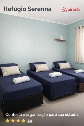 a room with three beds with blue sheets at Refúgio Serenna in Bebedouro
