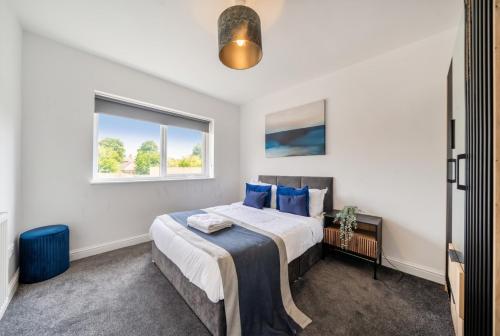 a bedroom with a bed with blue pillows and a window at St John's Flats, Newsome in Huddersfield