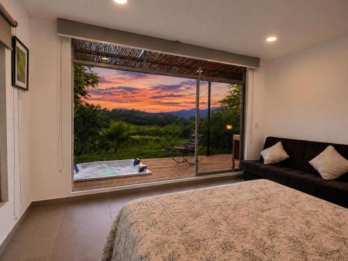 a bedroom with a large window with a view of a tub at Finca Samana in Tocaima