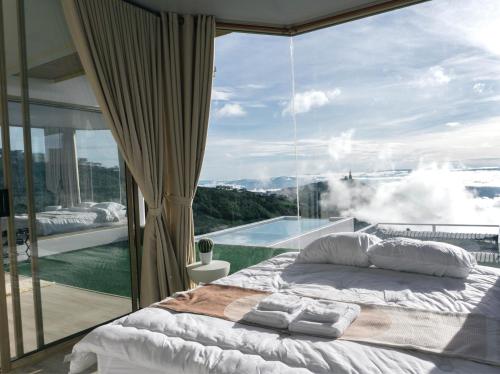 a bedroom with a bed and a large glass window at รีทรีท ภูทับเบิก in Ban Maeo Thap Boek
