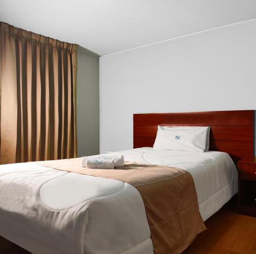 a bedroom with a large white bed with a wooden headboard at HOTEL MURCIA AREQUIPA in Arequipa