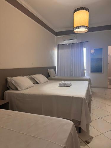 a hotel room with two beds and a window at Iter Hotel in Rifaina