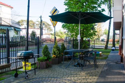 a patio with tables and a grill and an umbrella at Willa Focus in Mielno