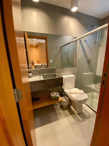 a bathroom with a toilet and a sink and a mirror at Beira Mar Japaratinga Brisa in Japaratinga