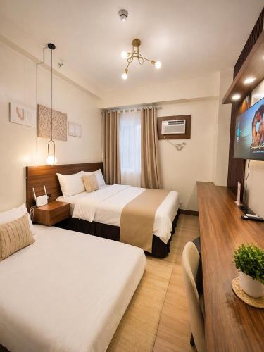 a hotel room with two beds and a flat screen tv at The Narci Suites in Manila