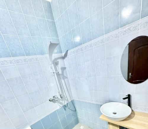 a blue tiled bathroom with a sink and a mirror at Résidence La Rose des Vents in Cotonou