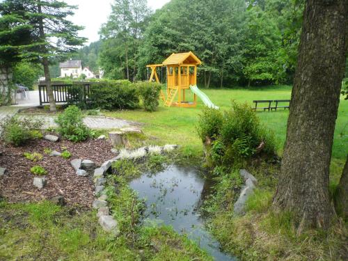 un parque con parque infantil y un árbol en Penzion v Infocentru, en Srbská Kamenice