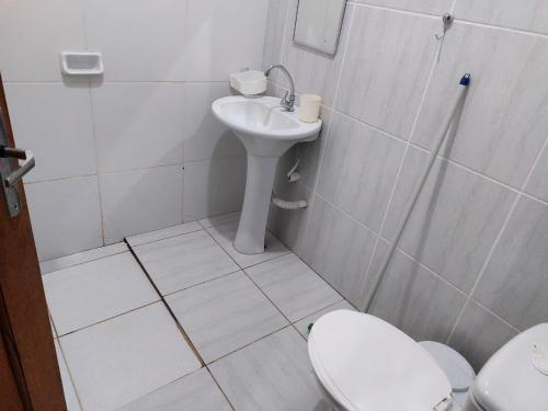 a white bathroom with a sink and a toilet at Casa Alter do Chão Com piscina in Santarém