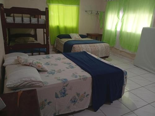 two beds in a room with green curtains at Casa Alter do Chão Com piscina in Santarém