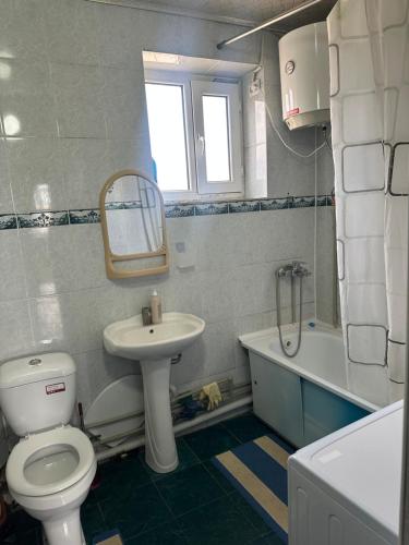 a bathroom with a white toilet and a sink at Грин сити in Balykchy