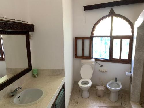 a bathroom with a toilet and a sink and a window at The Mousa House in Malindi