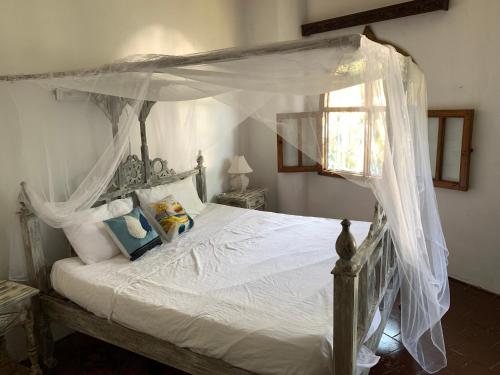 a bedroom with a canopy bed with white sheets and pillows at The Mousa House in Malindi