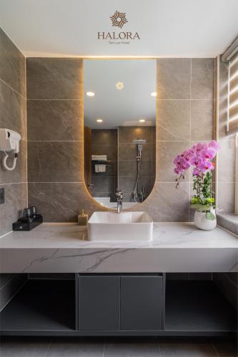 ein Badezimmer mit Waschbecken und Spiegel in der Unterkunft Halora Ten Lua Hotel in Ho-Chi-Minh-Stadt