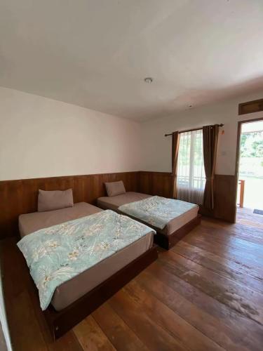 two beds in a room with wooden floors at Katra Sembalun in Sembalun Lawang