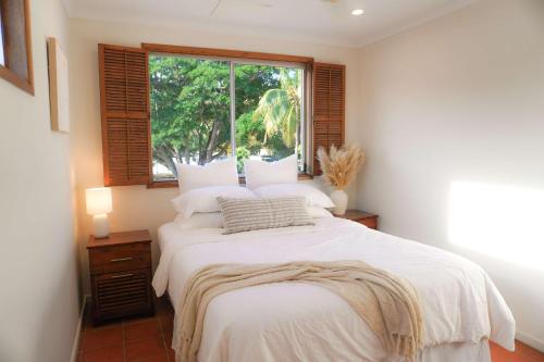 a bedroom with a large white bed with a window at The Balcony at Airlie in Airlie Beach