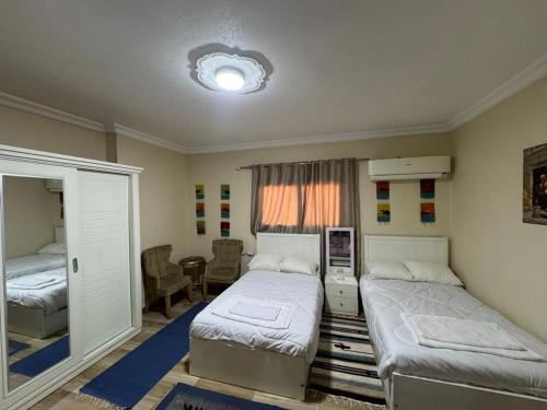 a bedroom with two beds and a table and a window at Akhnaton pyramids inn in Cairo