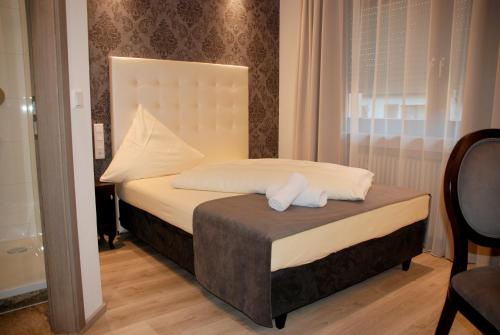 a bedroom with a bed with two towels on it at Hotel zur Linde in Hanau am Main