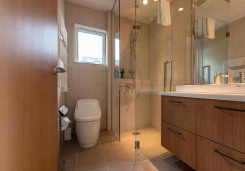 a bathroom with a toilet and a glass shower at The Orchards Niseko in Kutchan