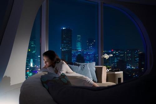 a woman laying on a couch in a room with a window at Conrad Beijing by Hilton in Beijing